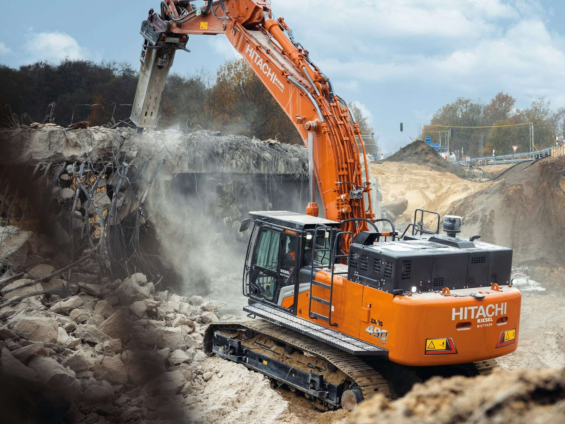 Orange Hitachi excavator breaking out concrete on a civils site